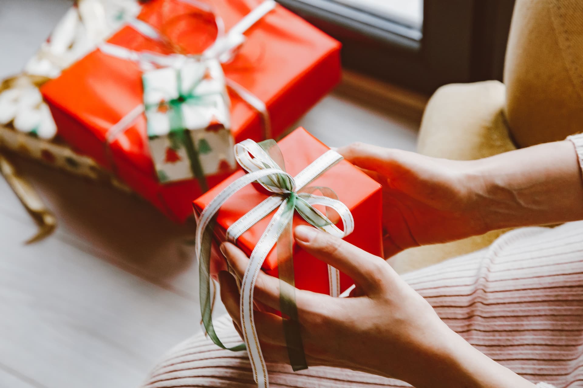 Hands holding a wrapped gift tied with a ribbon