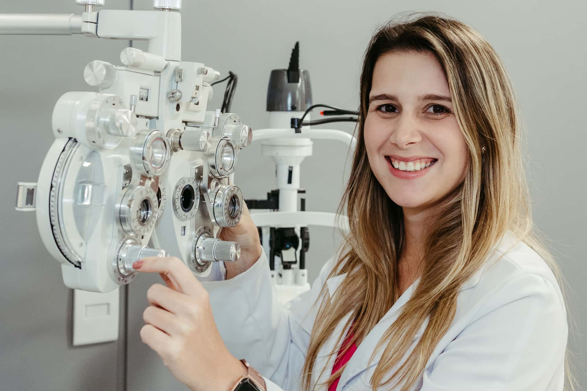 An optician using a phoropter in an exam room