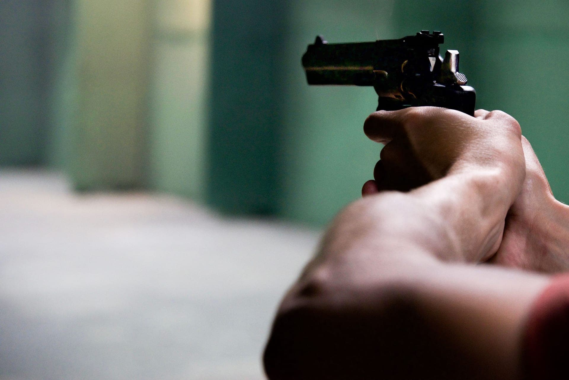 Hands aiming a pistol on an indoor shooting range