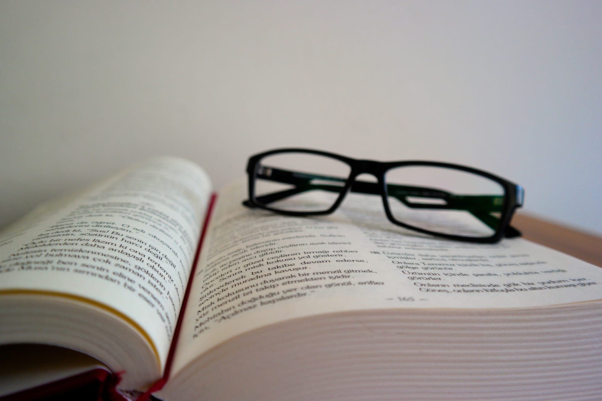 An open book with eyeglasses resting on top