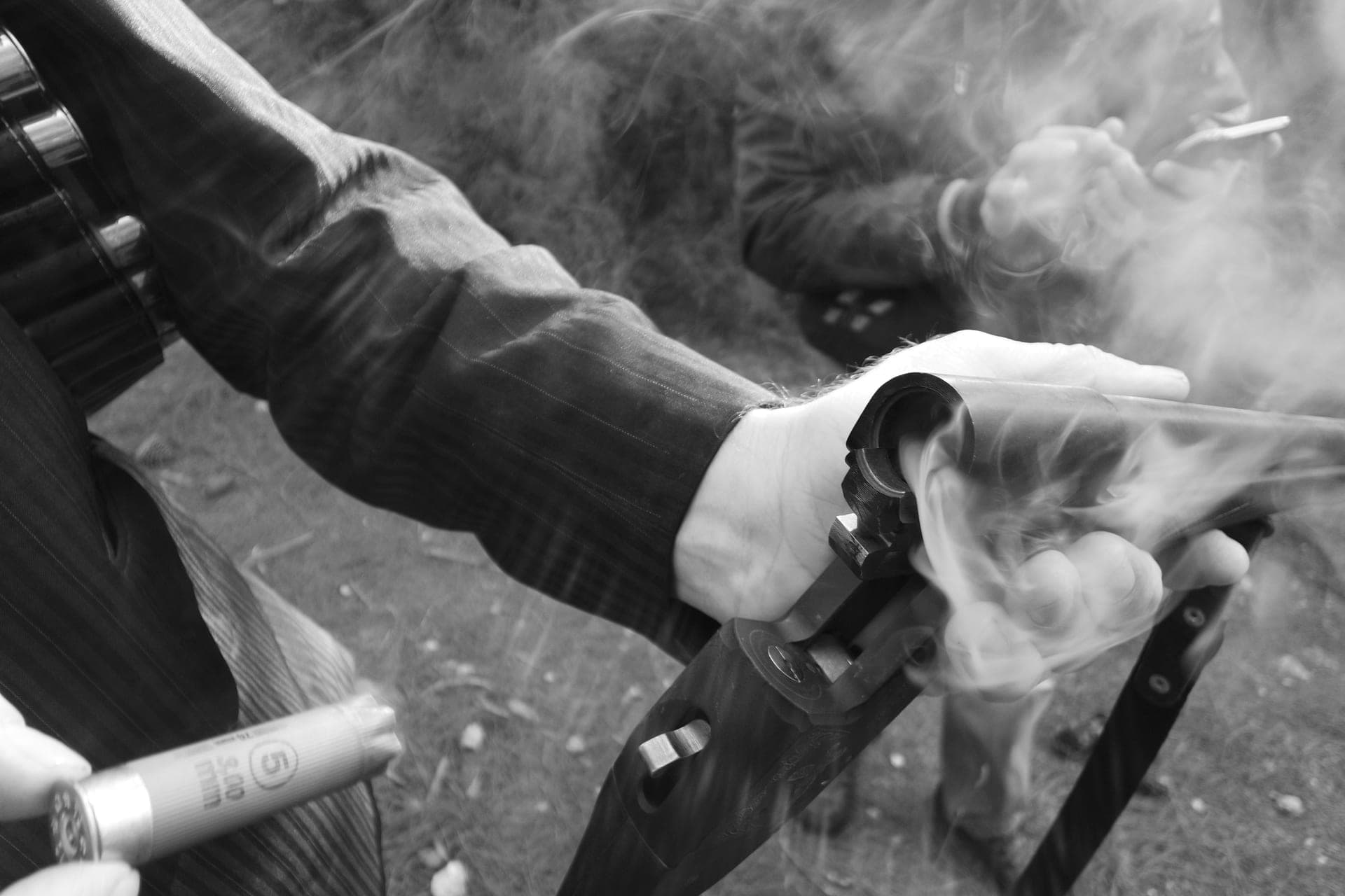 A hand holding a shotgun with smoke leaving the muzzle