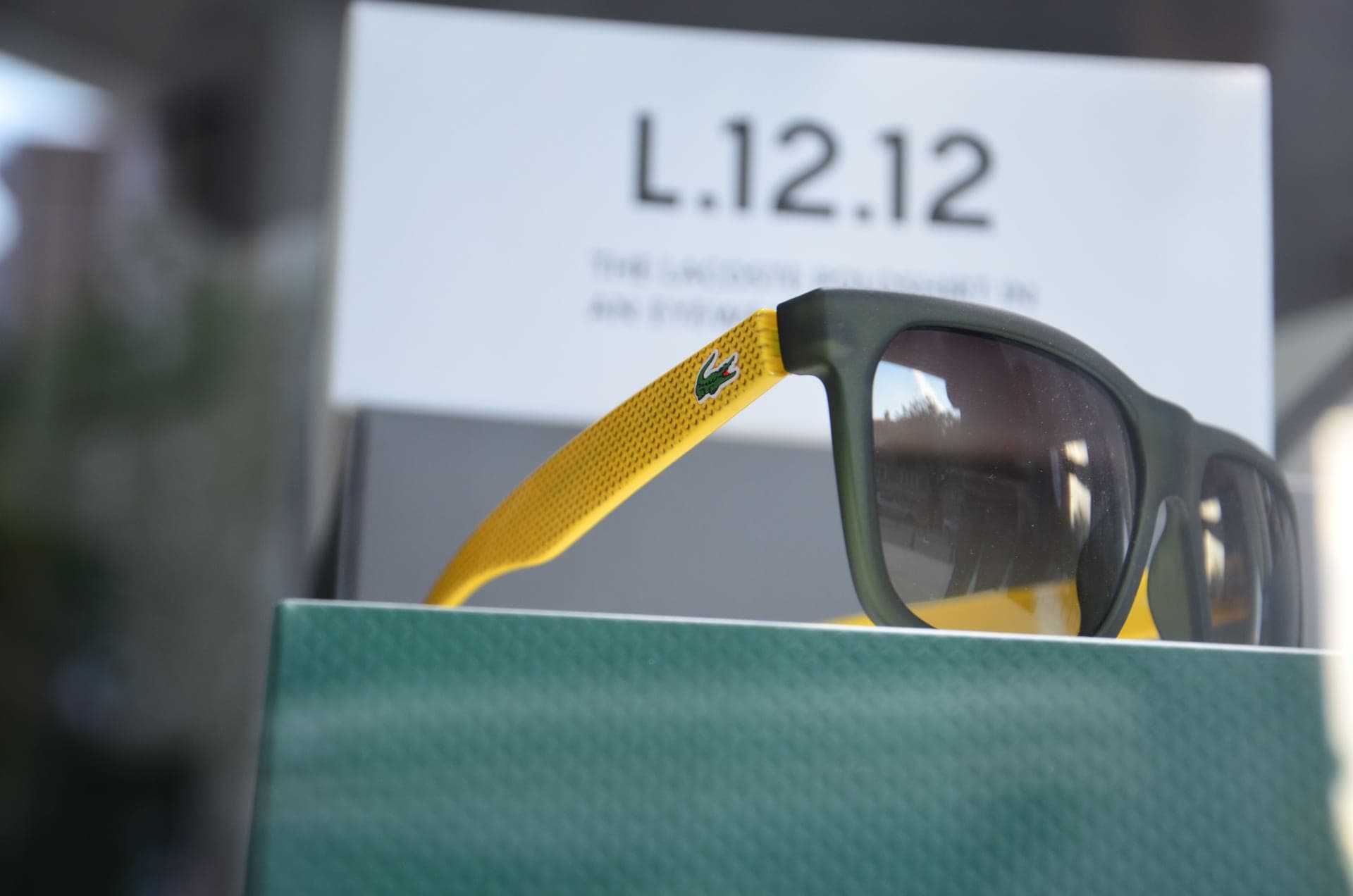 Sunglasses with green and yellow reflective lenses on a display