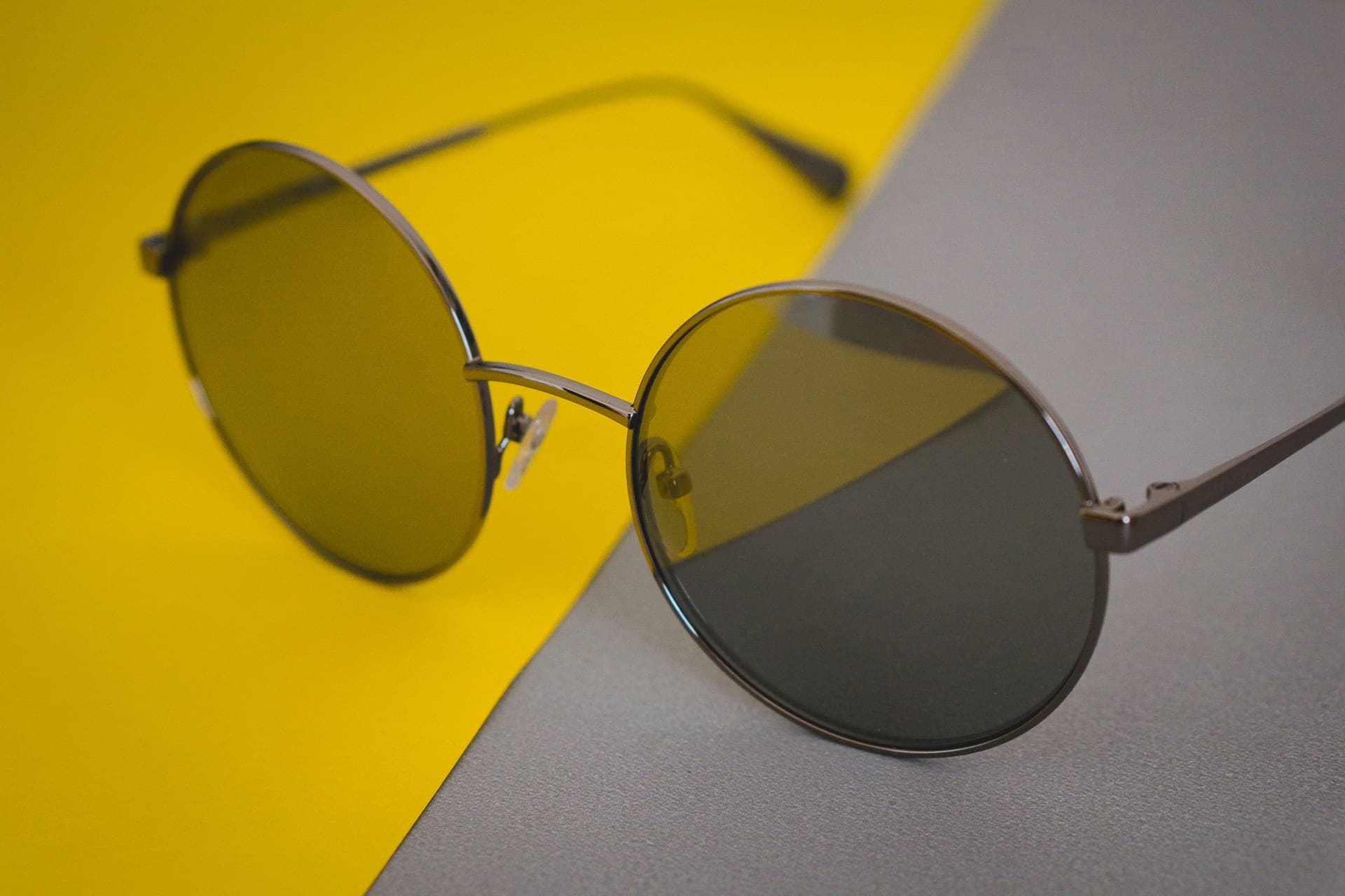 Round sunglasses on a yellow and gray background